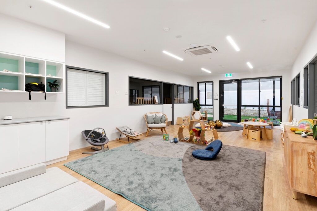 Nido Avondale Heights Living room with small wooden cupboards, transparent door, carpet, toys and windows