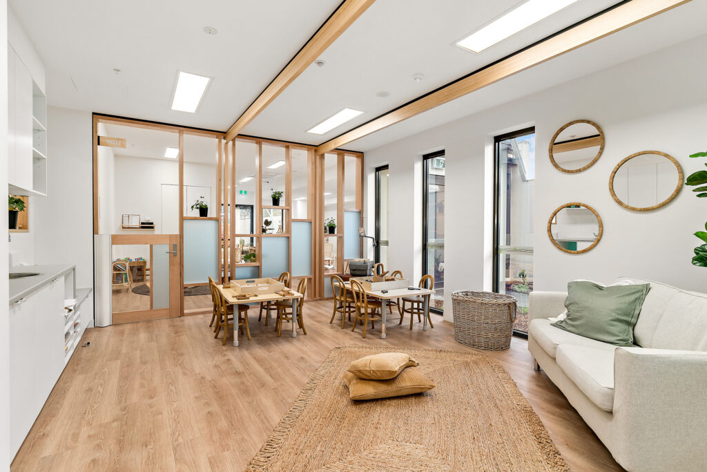 Nido Essendon Living room with small table, chairs, carpet, sofa, pillows, wooden drawers and mirrors