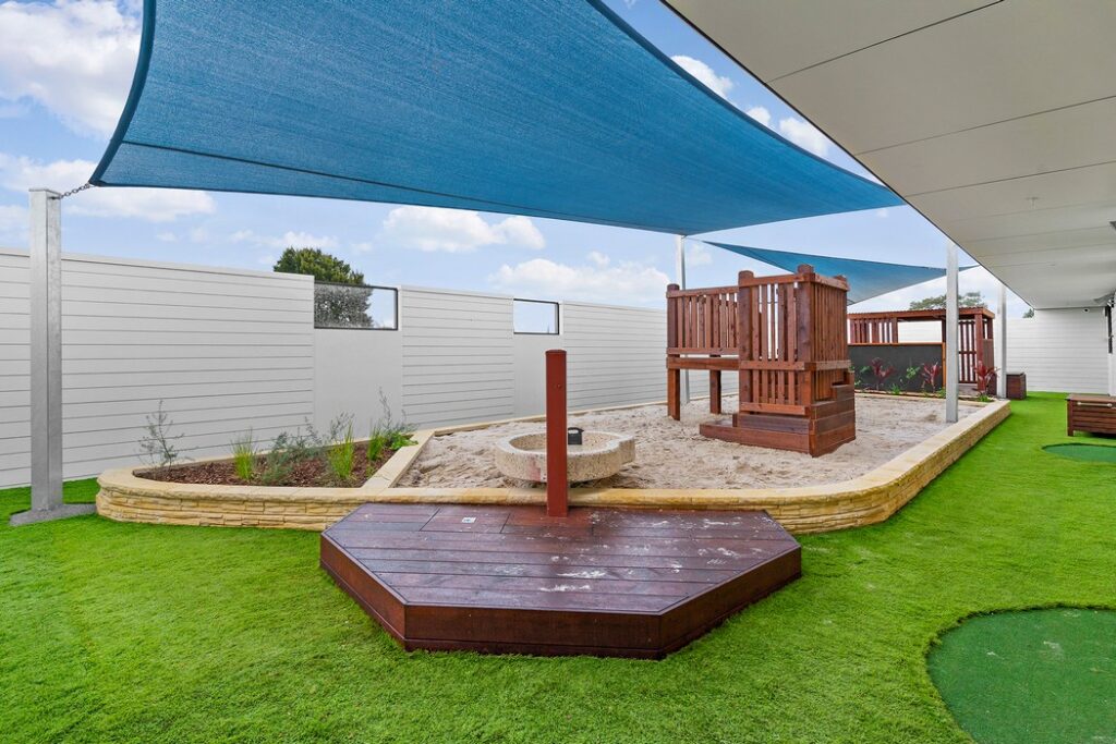 Nido Avondale Heights Center area covered with mud, small stone platform, wooden strings stand and small plants rest part is covered with green grass