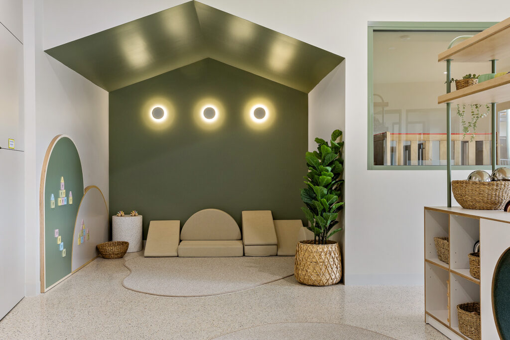 A vibrant playroom at Nido Butler Childcare Centre featuring a green wall and a clean white floor