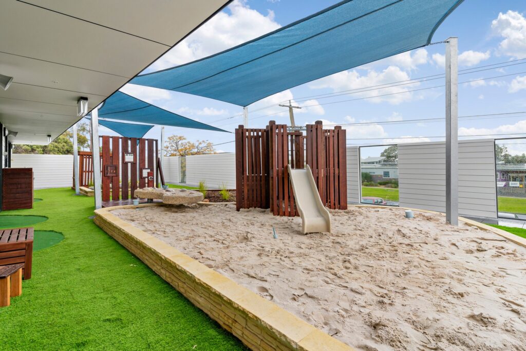 Nido Avondale Heights Area with green grass, small slide attach with wooden strings, center area covered with mud and small stone platform