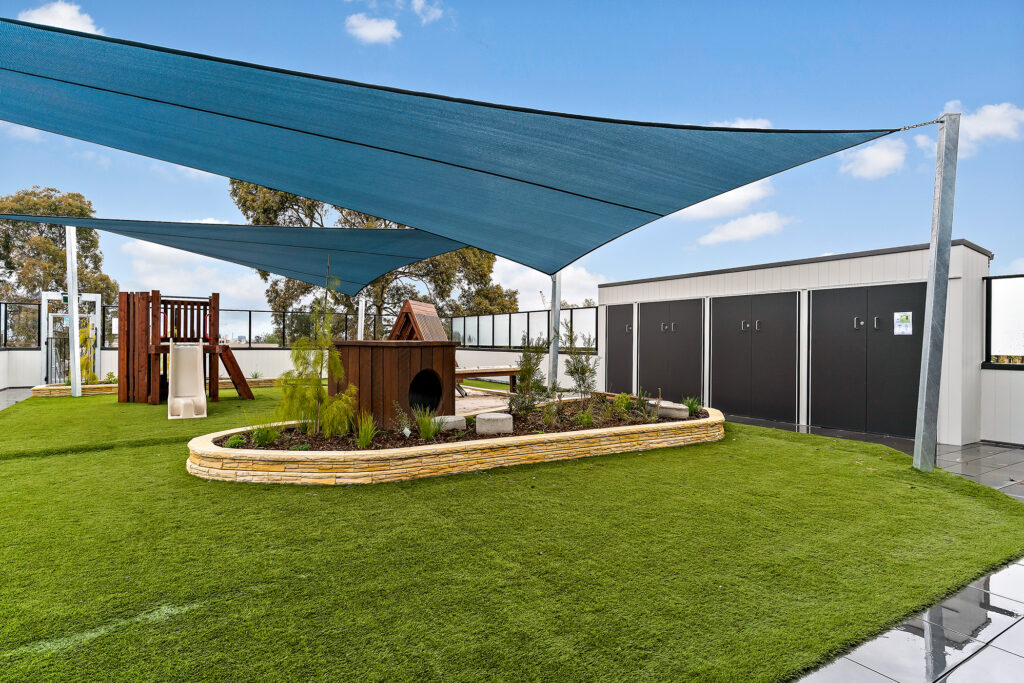 Nido Essendon Terrace with green grass, small plants around small box made of wood