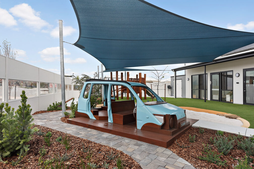 A blue car is situated under a metal canopy at Treeby South child care centre