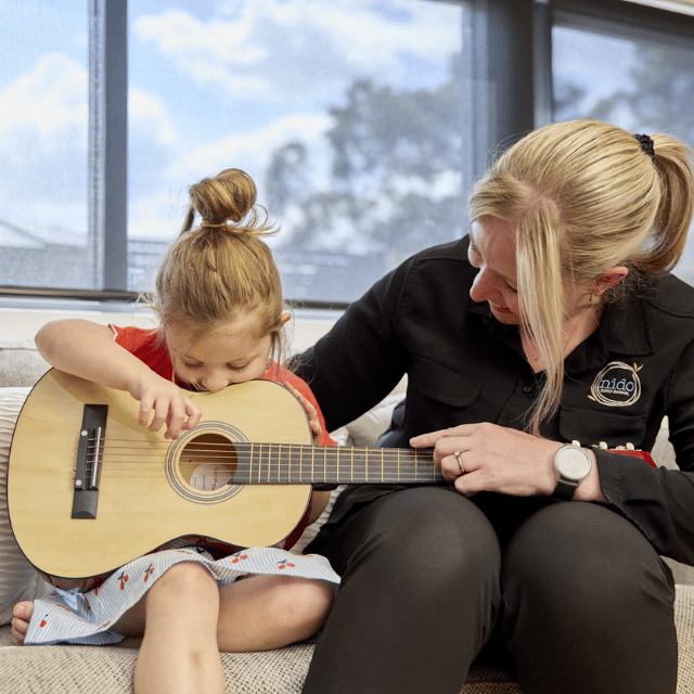 Child and Educator engaging in music program at Nido Belair childcare